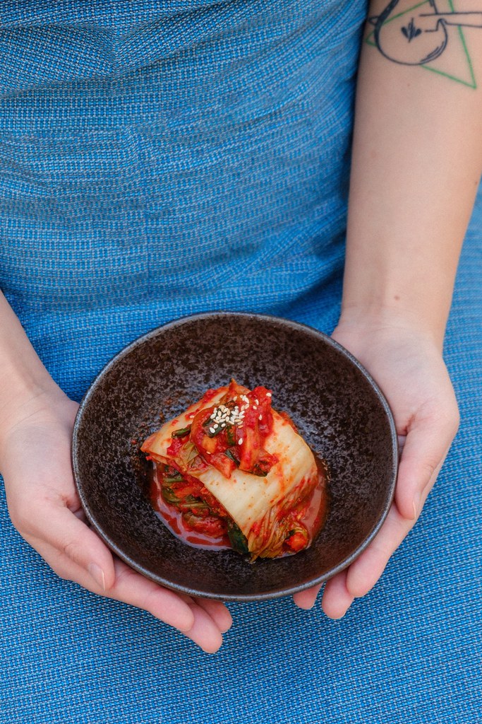 A bowl of kimchi in someone's hands. 