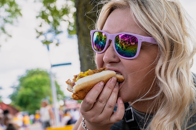 Blonde woman eats and chows down a footlong hot dog at the state fair in Minnesota