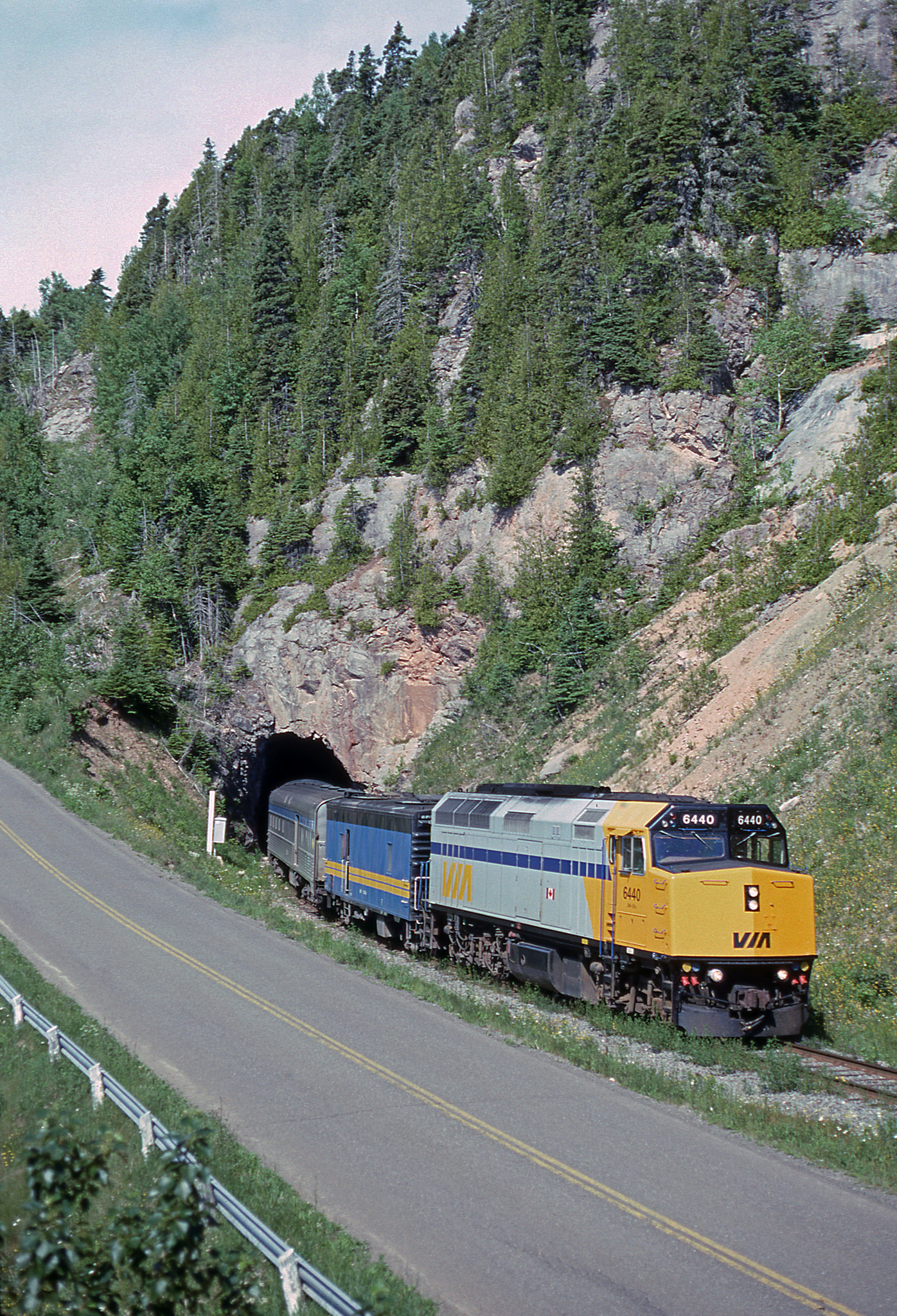 VIA # 16, the eastbound "Chaleur," exits the short tunnel just east of Port-Daniel. The train will terminate its run at Gaspé, which is located  at the end of Canadian National's line along the Baie des Chaleurs.

This photo was taken in my younger days when climbing a tree to "get the shot" was a doable proposition.


VIA # 16 "Chaleur"
Tuesday, July 3, 1990.

 