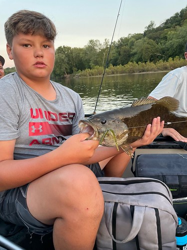 Photo of boy in a boat holding a smallmouth bass