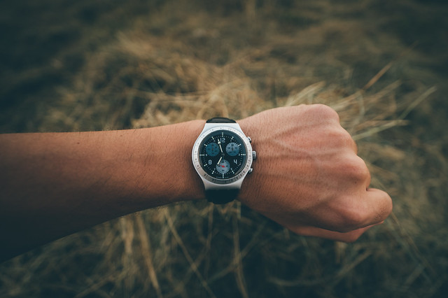 Analog wrist watch on a person's hand with hay in a blurry background