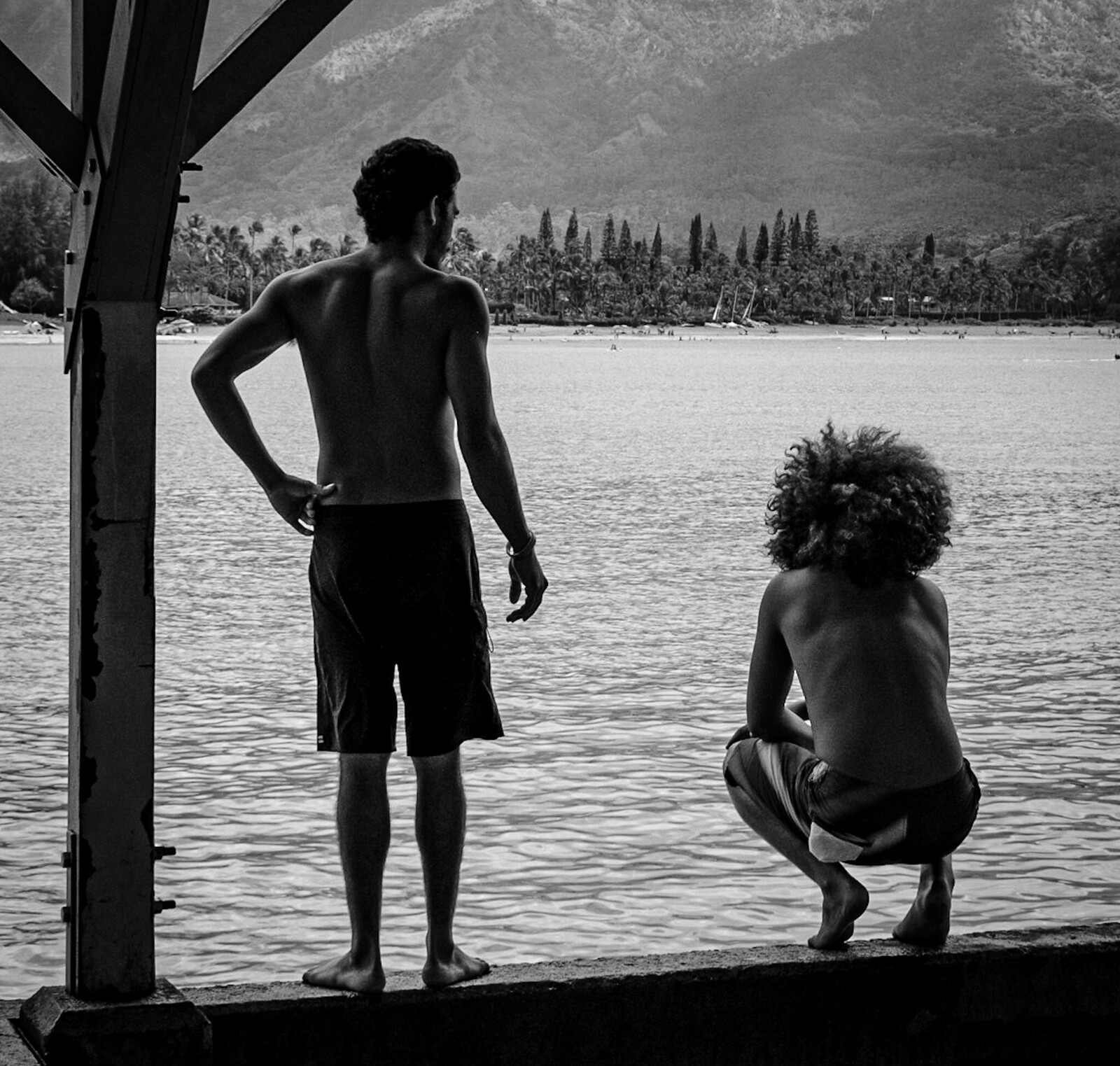 Young men contemplate jumping from the pier at Hanalei