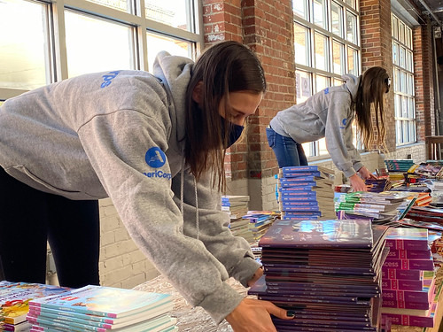 AmeriCorps volunteers stack books at ASTAR's annual community outreach event.