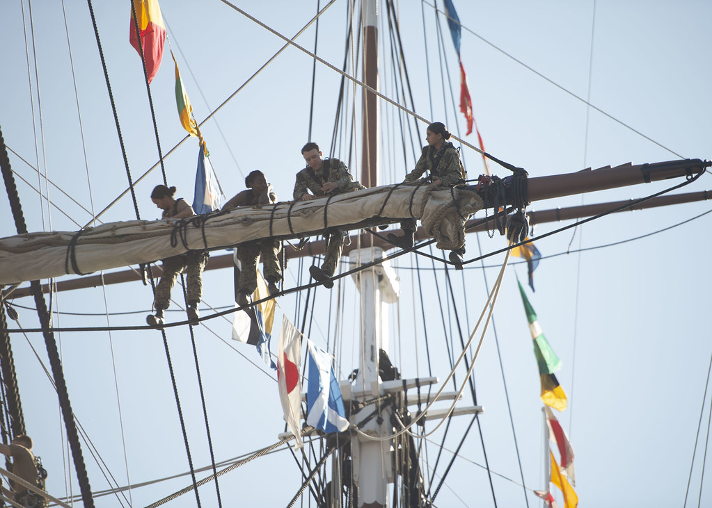 Sailors assigned to USS Constitution bend on Constitution's forward top sail.