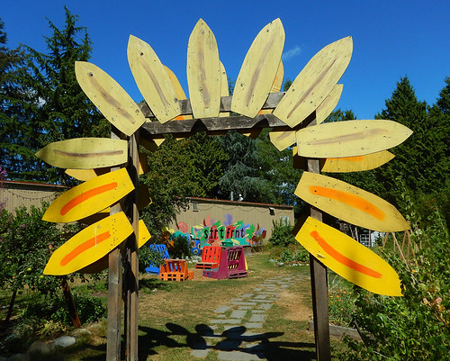 A 'petal gate' of a yellow flower frames the entrance of a community garden in Vancouver, BC