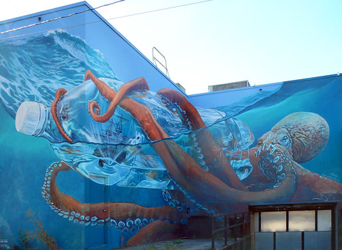 mural on a wall in Vancouver of an octopus clasping a plastic water bottle with a ship inside