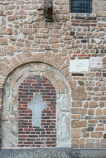 Grabstein von 1658 in einer vermauerten Rundbogentür und 2 romanische Memoriensteine in der Mauer der Südseite