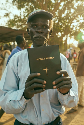 A man holds up the Mabaan Bible.