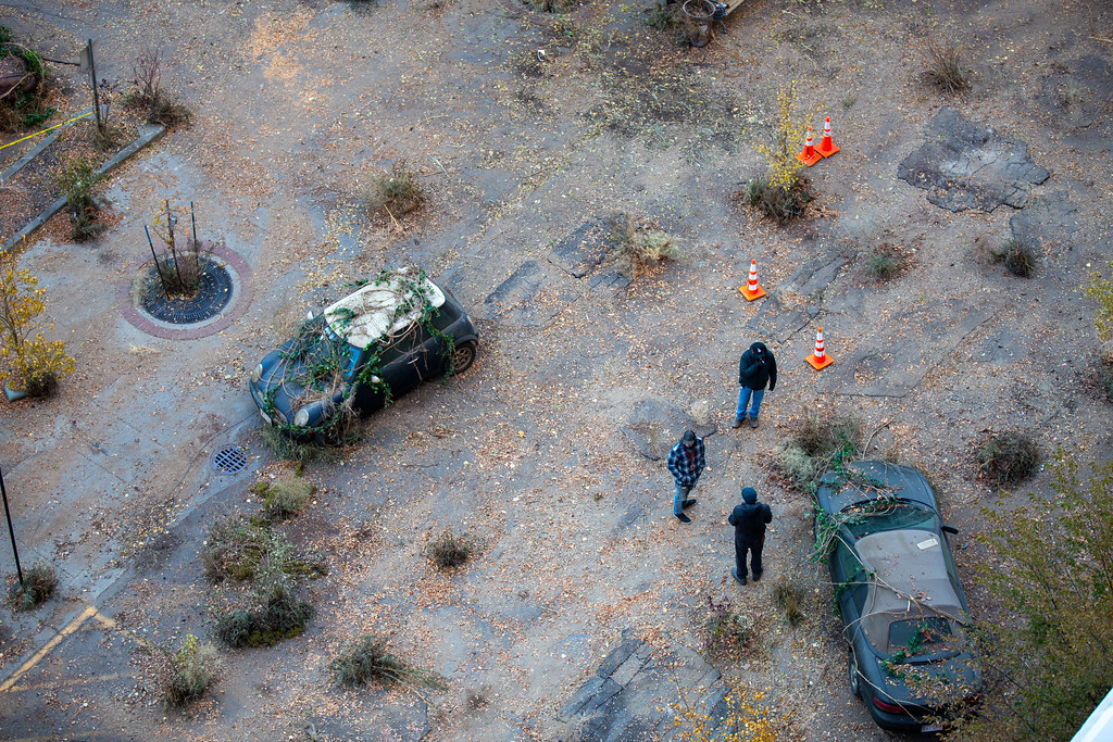 An overhead shot of film-crew members beside derelict cars on the set of The Last of Us