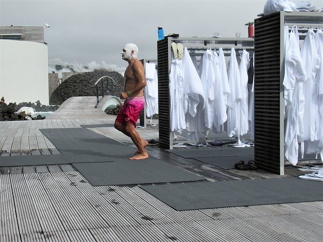 Man with head covered in silica, bathrobe racks at the Blue Lagoon, Iceland