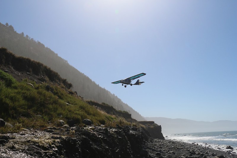 View of a pusher-prop ultralight airplane as it comes in for a landing on the airstrip at Miller Flat on the Loast Coast