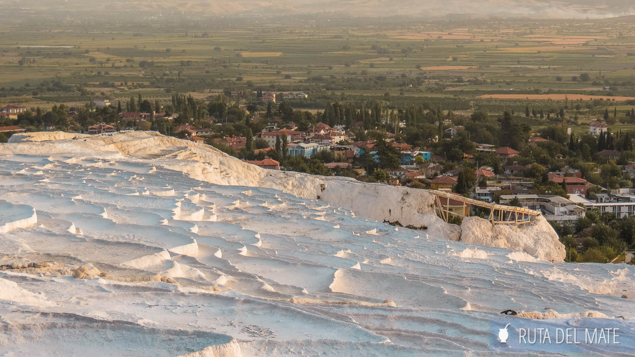 Travertines in Cappadocia in a 7 to 15 in Turkey Itinerary. The photo is taken from the top of Pamukkale and down. From the middle of the photo down, you can see the white pools, without water, of the travertines. From the middle to the top, you can see the city of Pamukkale.