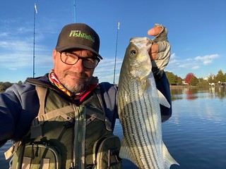 Photo of man in a kayak holding a large striped bass