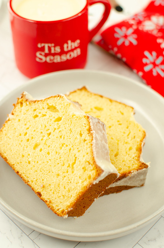 glazed eggnog bread on a white plate; red mug with eggnog in the background