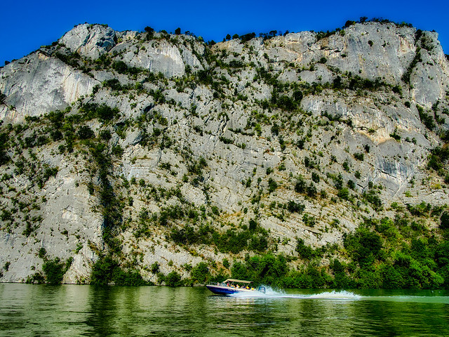 Small boat cruising near high cliffs