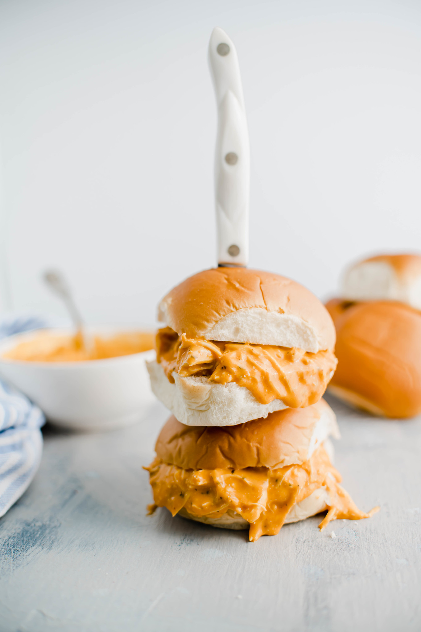 Two buffalo chicken sandwiches stacked on top of each other with a knife stuck into them.