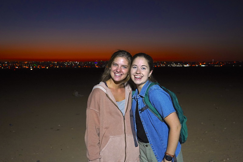 Evann and her friend Stephanie smiling on the desert at sunset. 