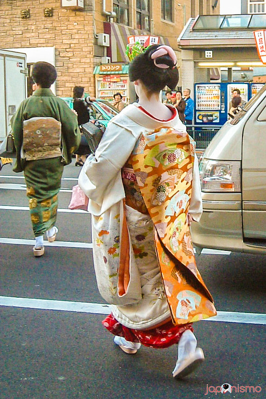Maiko el día del Kaomise, con obi larguísimo, con una geiko caminando delante, con un obi de lazo más sencillo