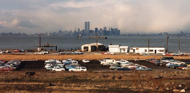 The threatening clouds of an impending thunderstorm over Jersey City & Manhattan from Staten Island, where the sun was still shining brightly. Abandoned railroad tracks and a parking lot filled with colorful cars. New York. April 1986