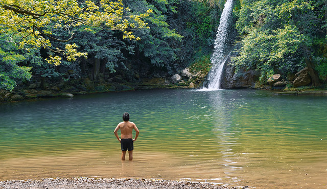 Man admiring waterfall in a river lagoon in Catalonia, Spain