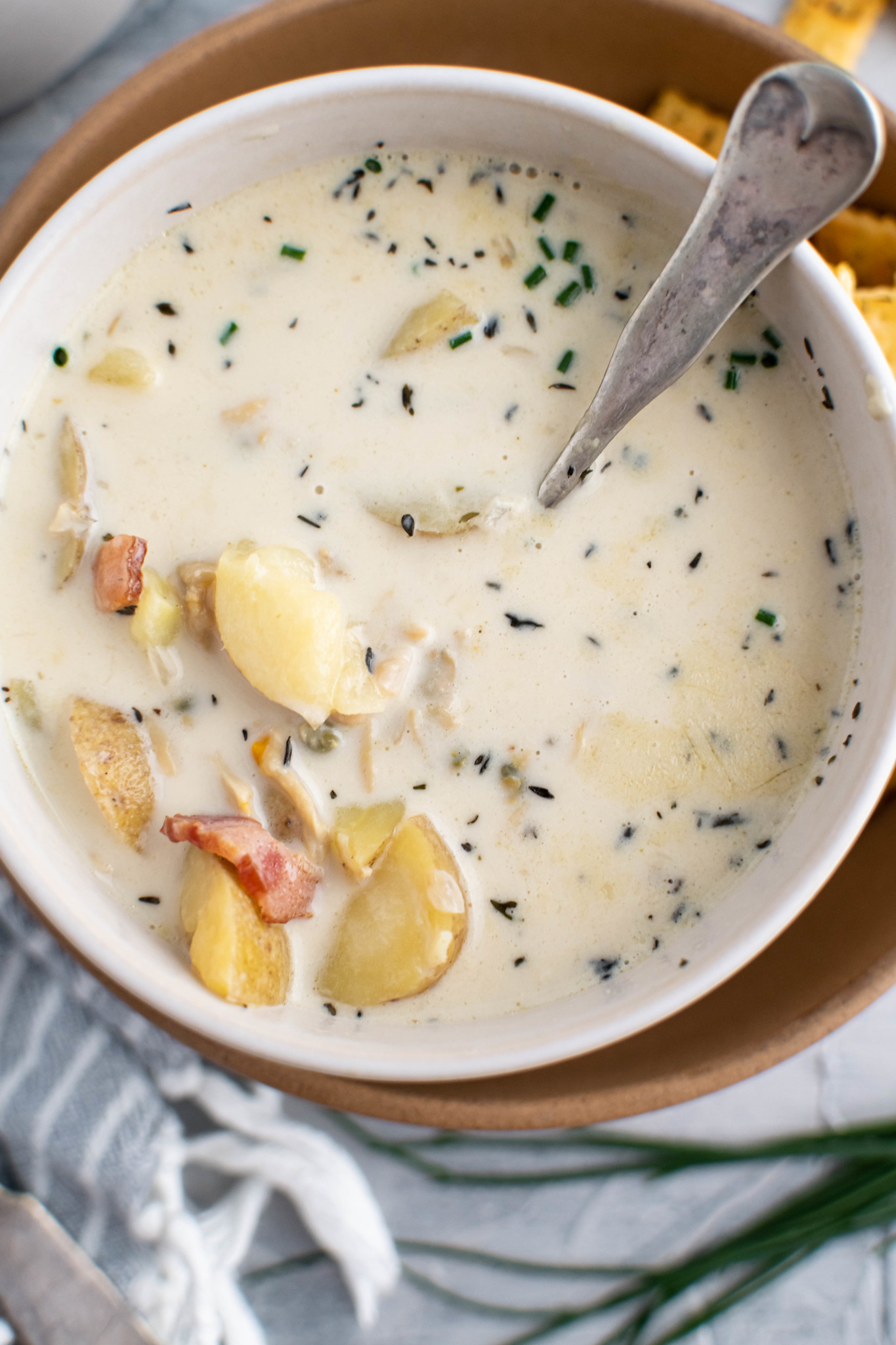 Close up photo of clam chowder in a white bowl.