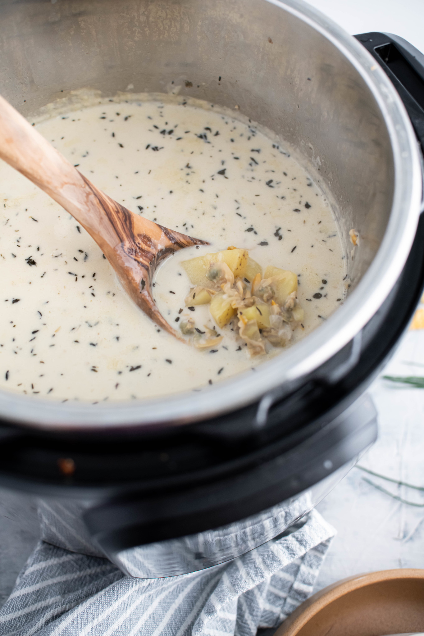 Ladle lifting spoon of clam chowder out of the instant pot.