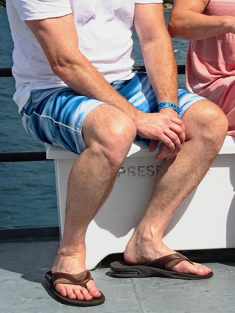 Man seated with leather flip flops.