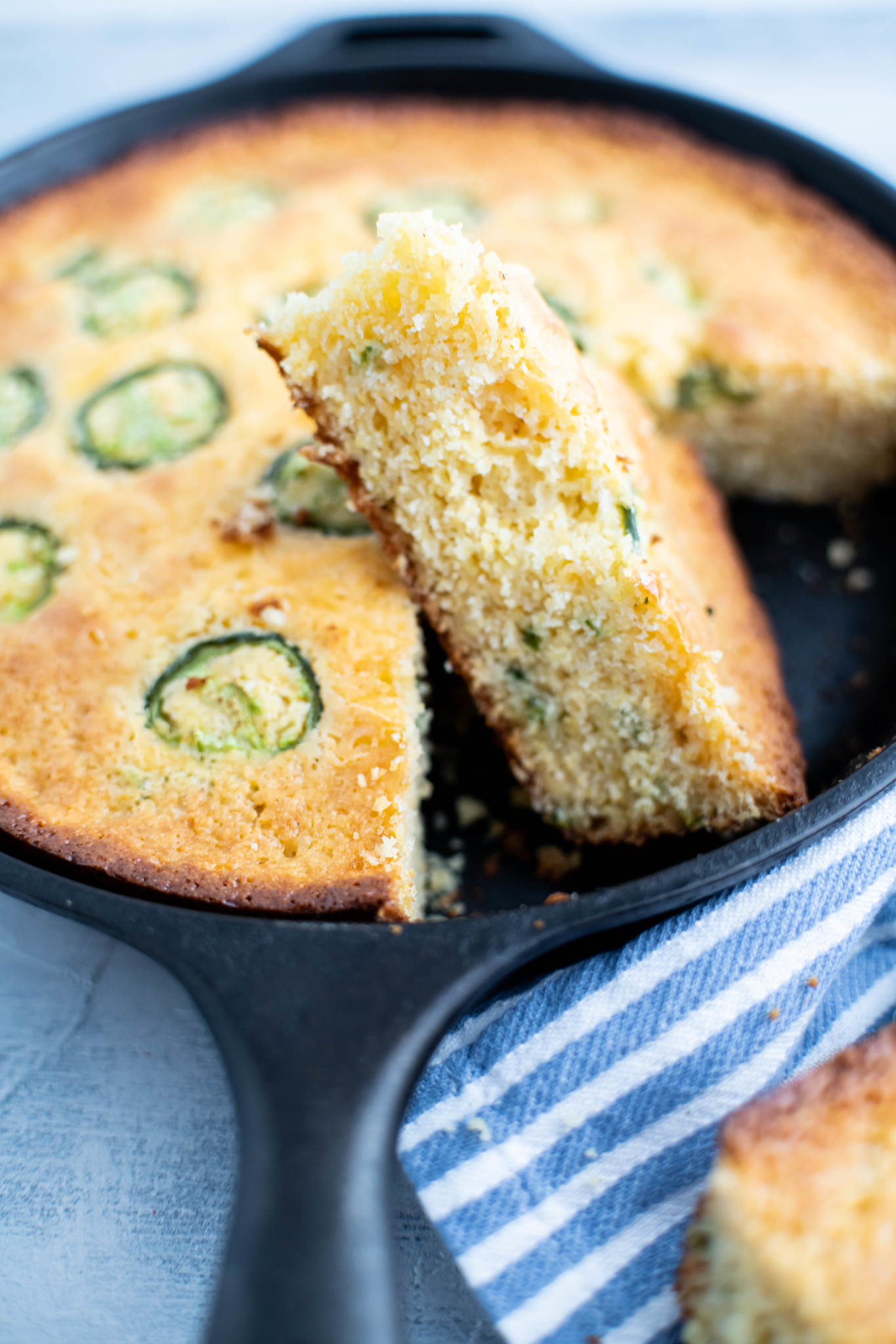 Slice of jalapeno cornbread turned on its side in the cast iron skillet.