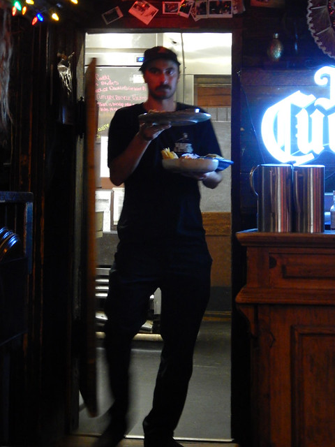 Waiter coming out the kitchen door with a loaded tray at the Magpie & Stump in Banff, Canada