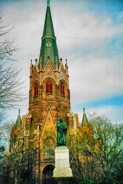 A bronze statue of Martin Luther and the Gothic Revival tower of Luther Place Memorial Church  - Washington DC-