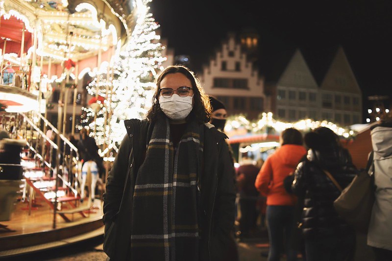 Trinidy bundled up in front of the Frankfurt Christmas carousel, all lit up at night.