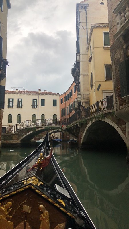 The pointed front end of a gondola going down a narrow canal in Venice.