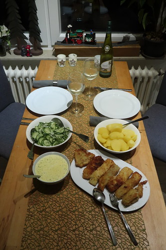 Paniertes Seelachsfilet mit Sauce Dijon zu Salzkartoffeln und Gurkensalat (Tischbild)