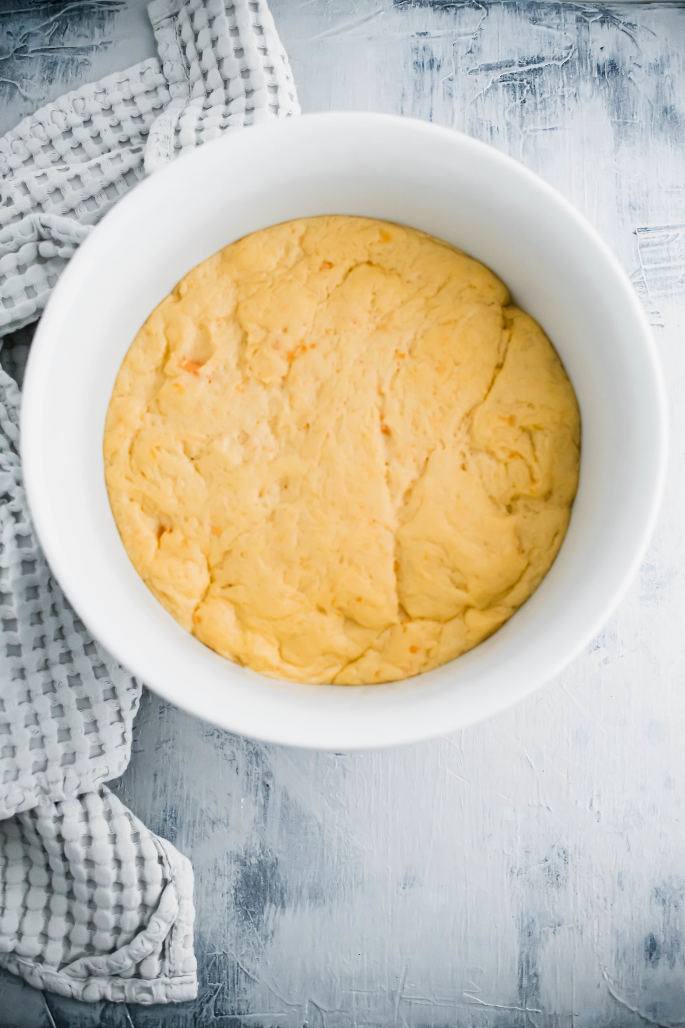 Sweet potato roll dough in a large white bowl after it has risen.