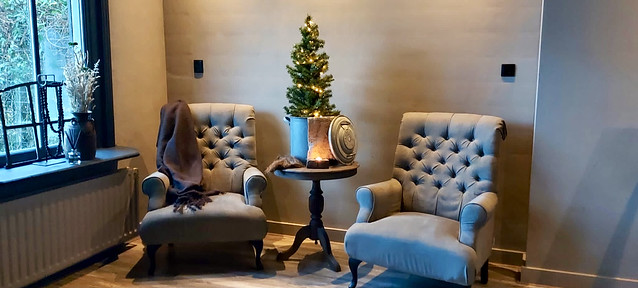 Landelijke fauteuils zwarte kozijnen kerstboompje op wijntafel oud stalraampje in vensterbank