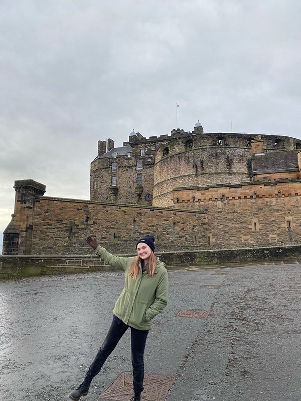 Macy posing in front of Edinburgh castle on a cloudy day.