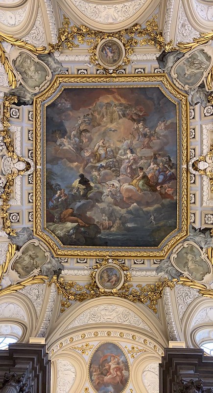 High arched ceilings with gold garnish wrapping around the various paintings that surround the large angelic painting.