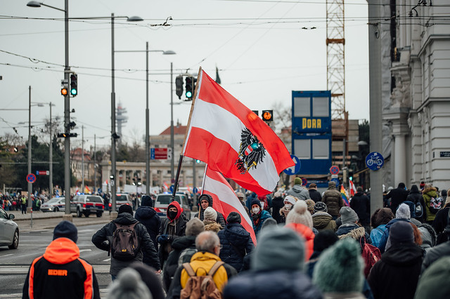 Demonstranten bei Demo gegen Impfzwang halten österreichische Flaggen