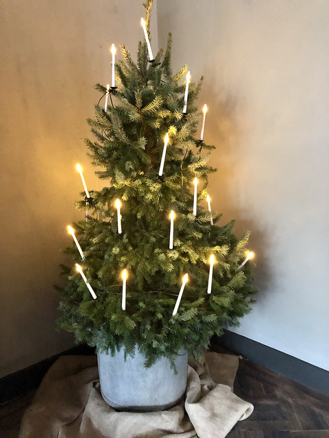 Kerstboom met kaarsen zonder ballen in zinken pot op jutekleed op visgraatvloer