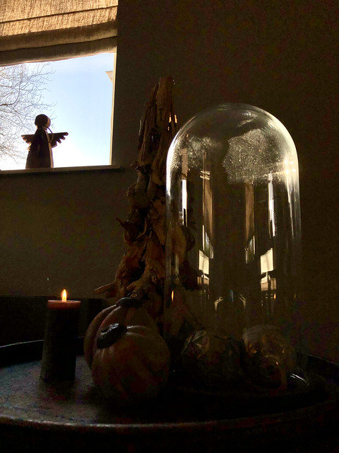 Glazen bol met kerstdecoratie op dienblad houten beeldje engel in de vensterbank