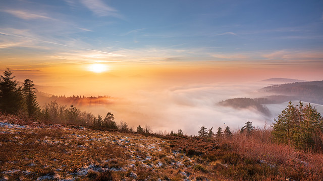 The last warm rays of the sun meet the cool fog over the Murg valley in the Black Forest