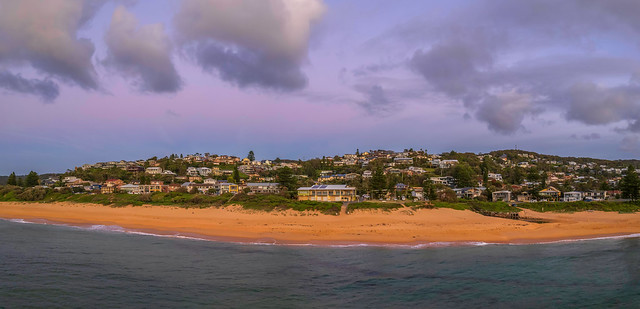 Panorama sunrise seascape with surf club, houses and clouds