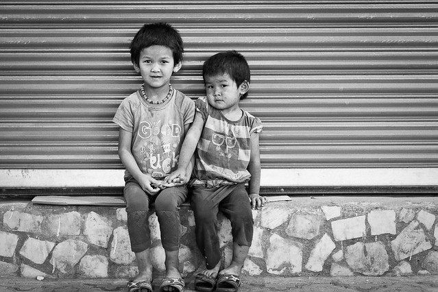 Two young girls sit by a roller door in Osh, Kyrgyzstan