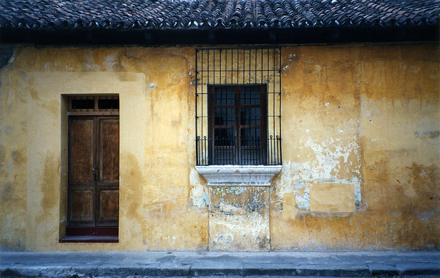 Decorative barred window in a pale gold wall in Antigua, Guatemala