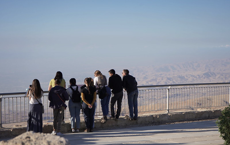 Students standing against a railing looking out at the desert land and mountains.