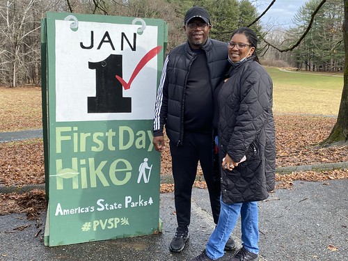 Photo of two people next to a First Day Hike sign on a trail