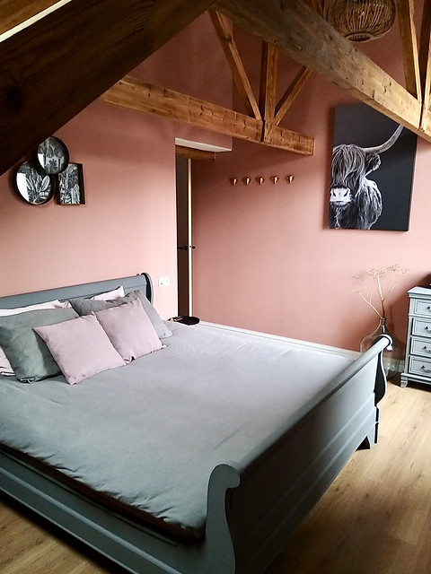 Roze muren landelijke slaapkamer Schotse Hooglander schilderij houten bed gebinten in het zicht