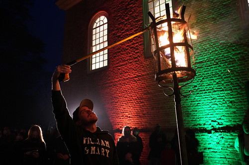 A young man lights one of the festive cressets (wood-burning torches) that keep the crowd warm during W&M's annual Yule Log ceremony.