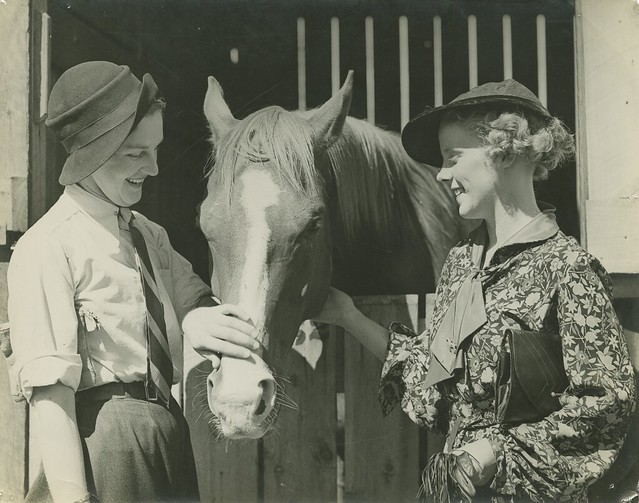 Two young ladies admire a horse at the racetrack