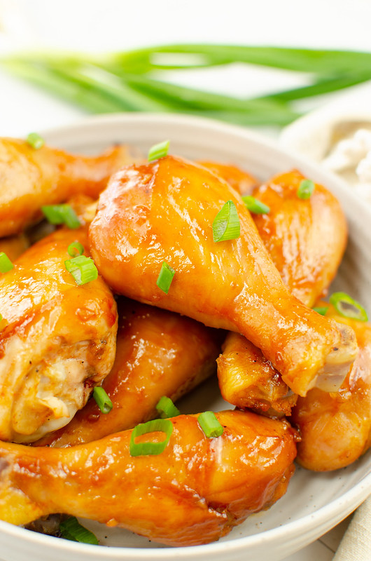 Chicken drumsticks with a sweet and sour sauce and green onions on top